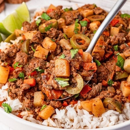 A spoonful of seasoned ground beef, potatoes, olives, and rice.