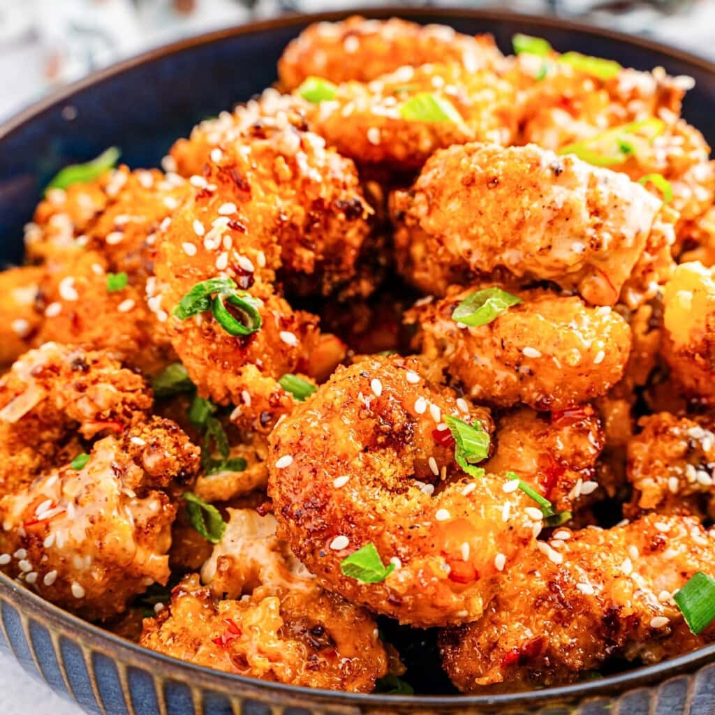 Crispy fried shrimp pieces topped with sesame seeds and chopped green onions.