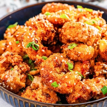 Crispy fried shrimp pieces topped with sesame seeds and chopped green onions.
