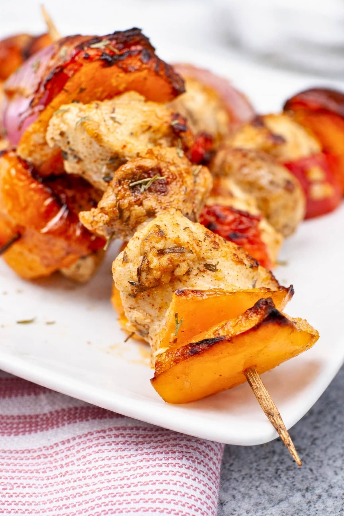 Grilled chicken and vegetable skewers on a white plate.