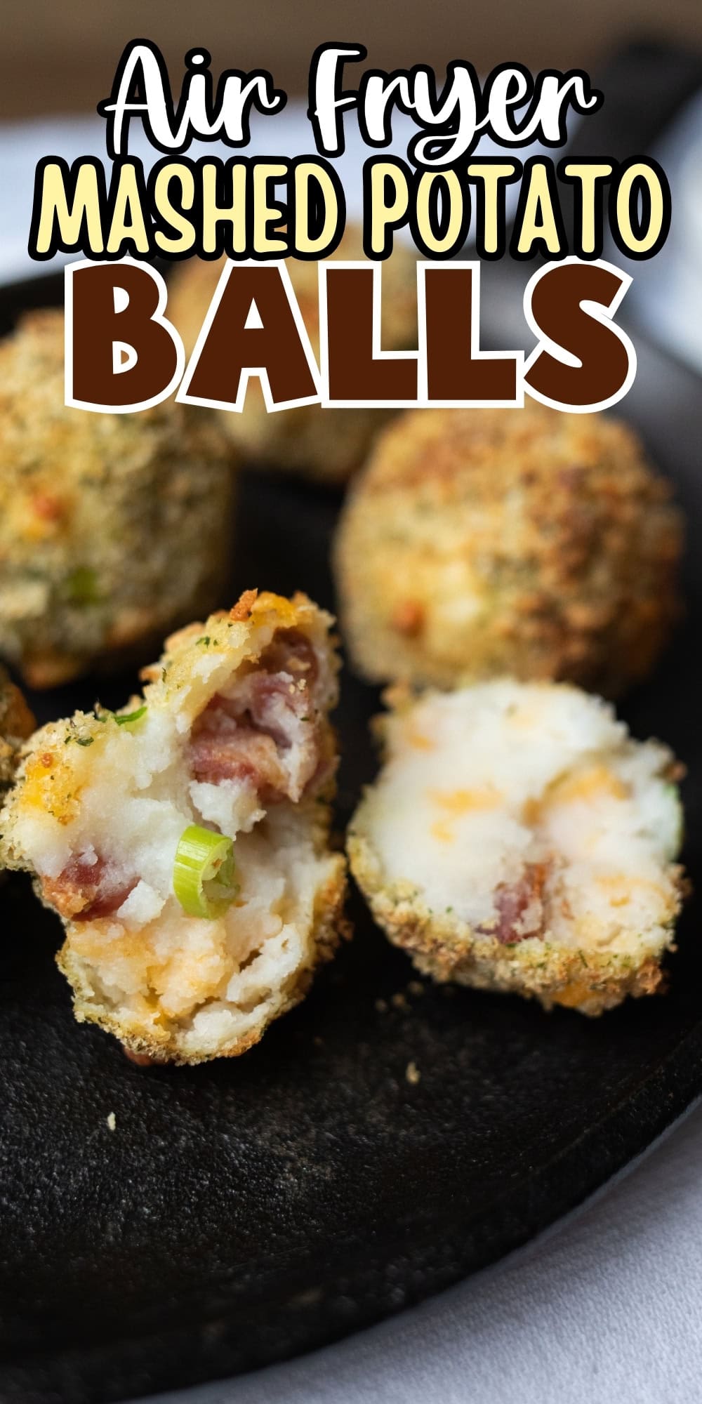 Mashed potato balls with bacon and green onions on a black plate.