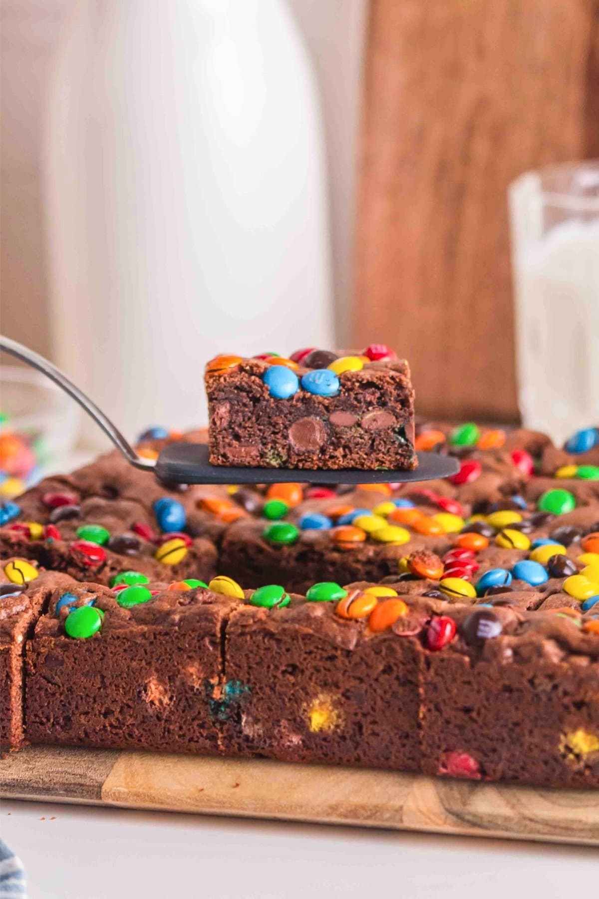 A spatula holds a brownie square topped with colorful candy-coated chocolates.