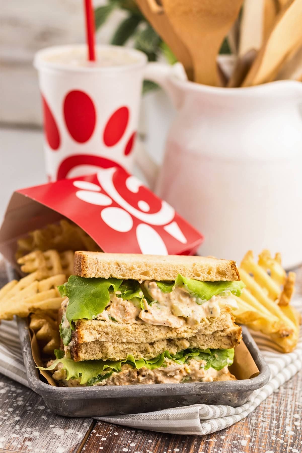 Chicken salad sandwich with waffle fries and a drink in Chick-fil-A packaging.