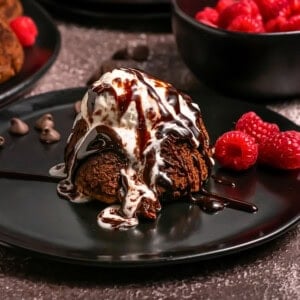 Chocolate lava cake with melting ice cream, chocolate sauce, and fresh raspberries.