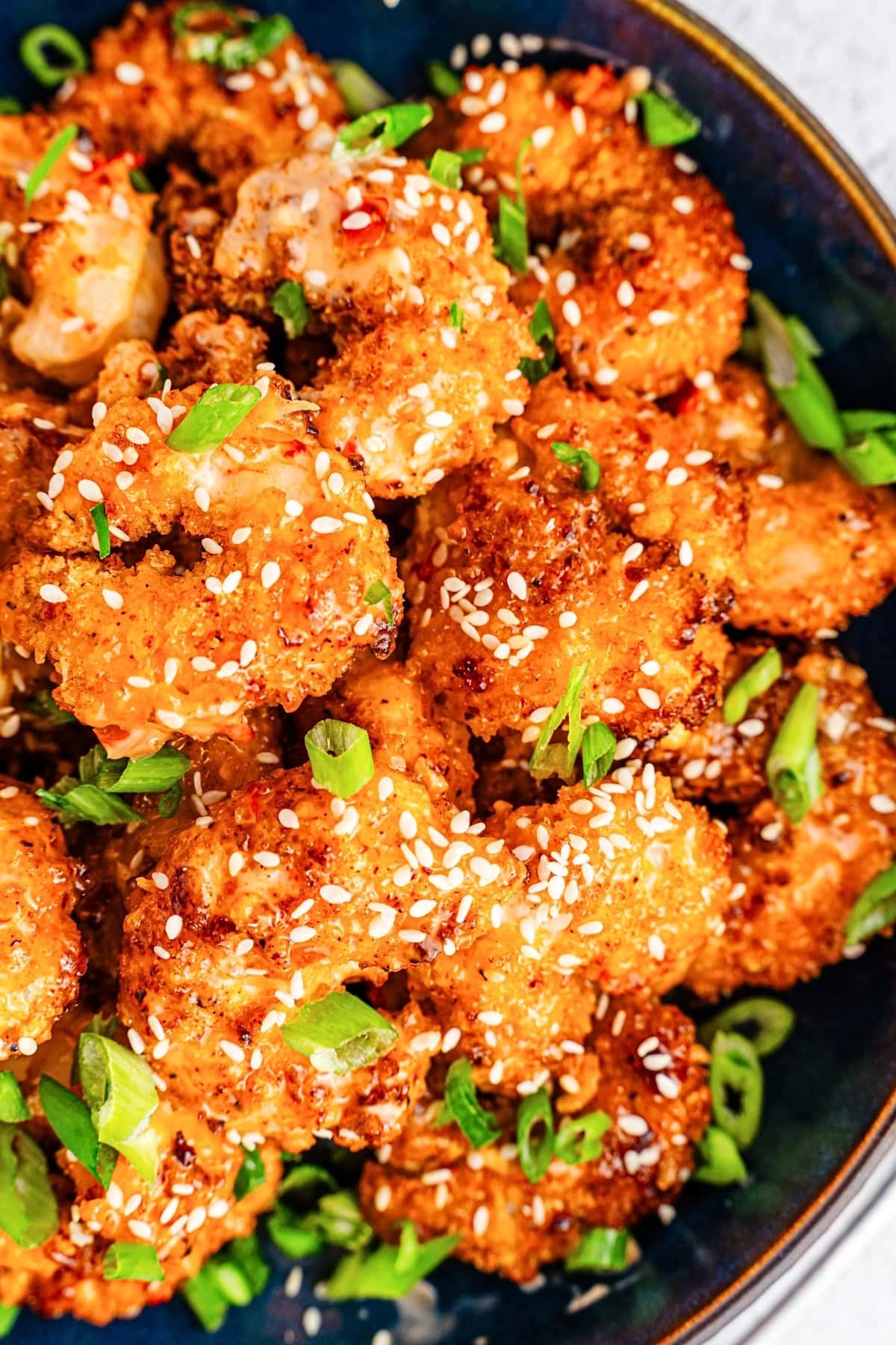 Crispy fried shrimp garnished with sesame seeds and chopped green onions.