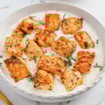 Seared salmon pieces in creamy white sauce, garnished with fresh dill.