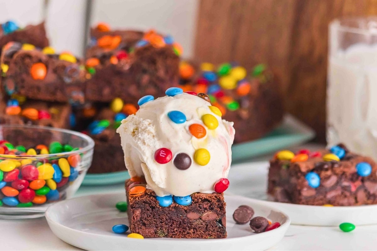 A brownie topped with vanilla ice cream and colorful candy-coated chocolates.