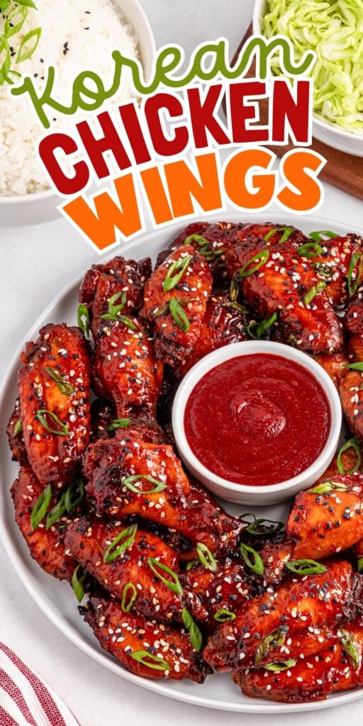 A plate of Korean chicken wings with sauce, rice, and shredded cabbage.