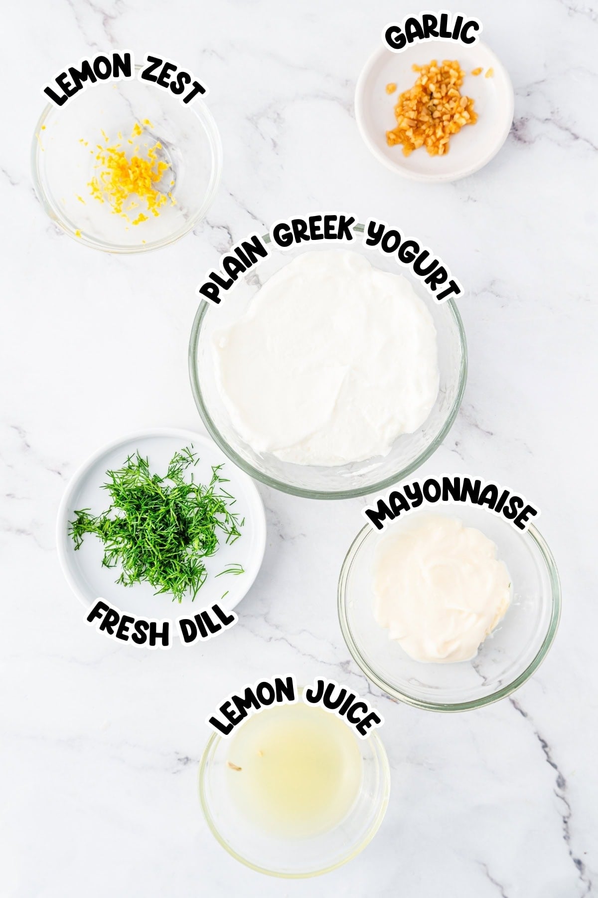 Bowls of lemon zest, garlic, Greek yogurt, dill, mayonnaise, and lemon juice.
