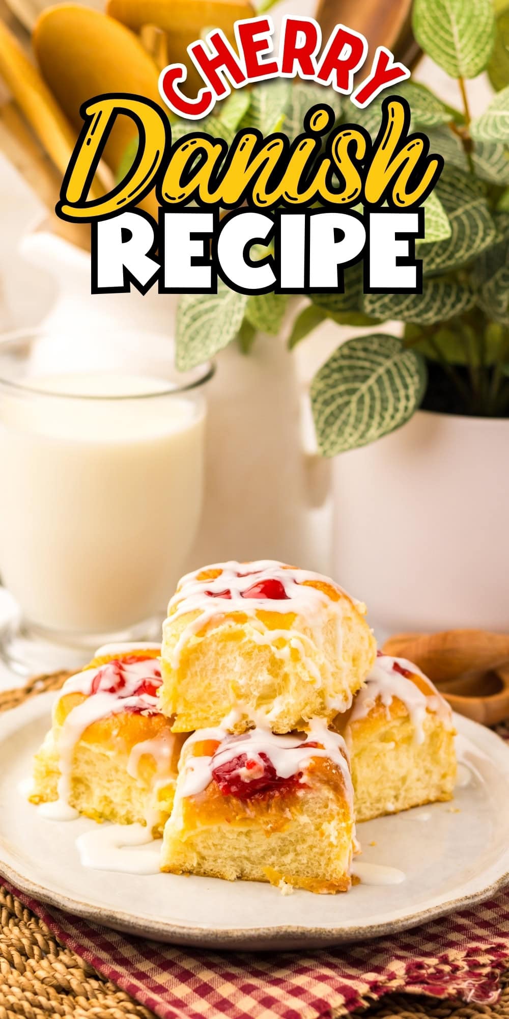 Three cherry Danish pastries with icing on a plate, glass of milk in background.