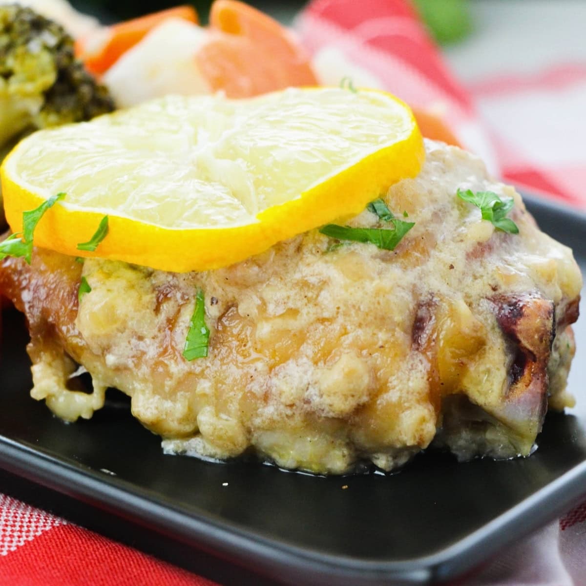 Chicken topped with creamy sauce and lemon slices, served with vegetables.