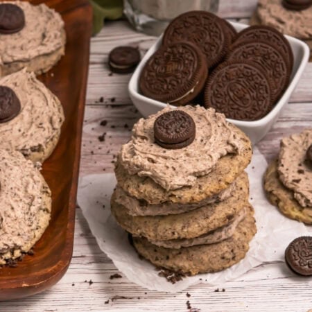 Stack of cookies with cream and mini chocolate cookie on top, next to a bowl of cookies.