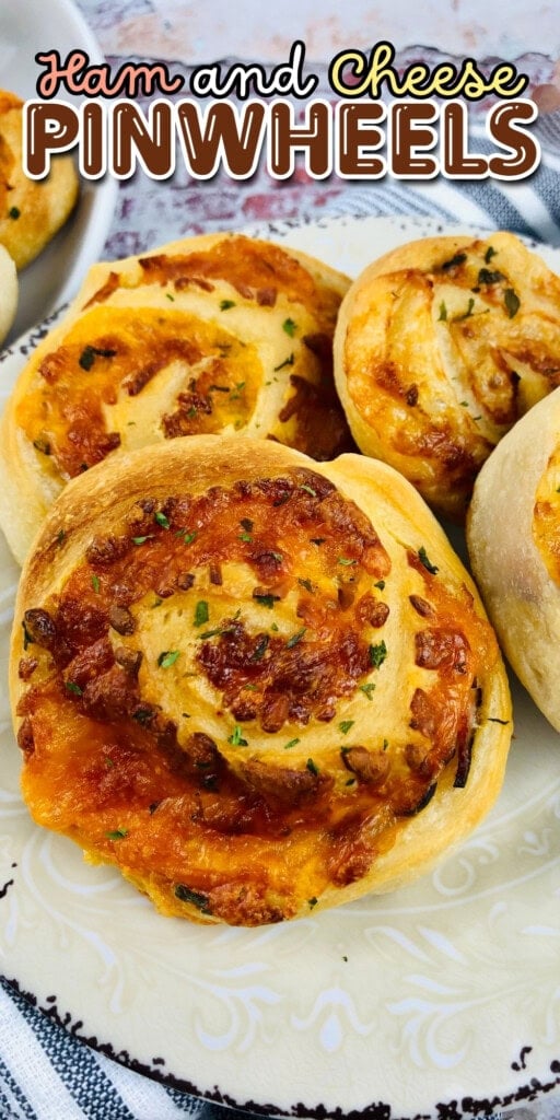 Ham and cheese pinwheels on a decorative plate with herbs sprinkled on top.