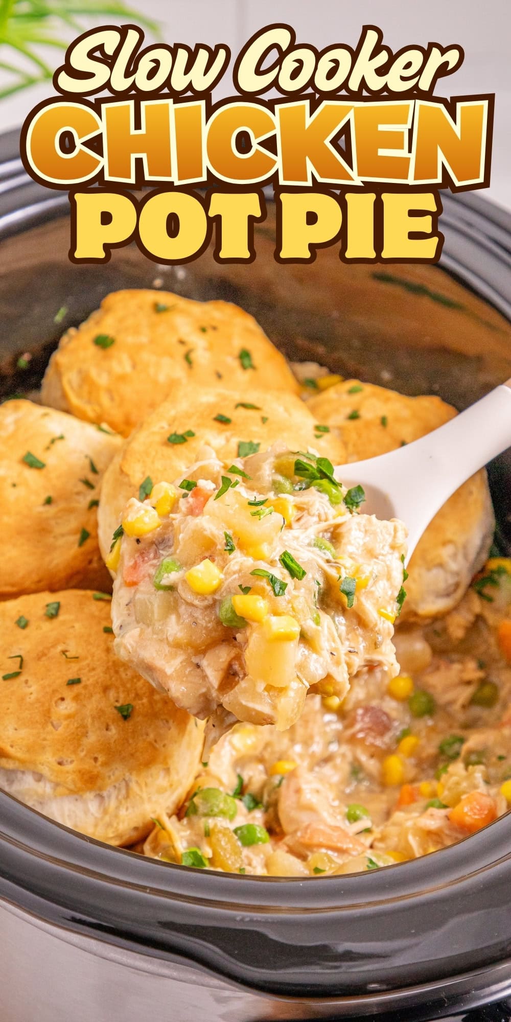 A spoon scoops chicken pot pie filling from a slow cooker topped with biscuits.