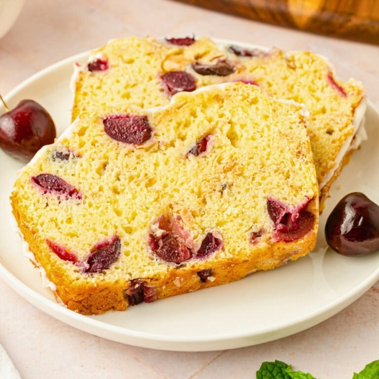 Two slices of cherry bread with visible cherry pieces on a white plate.