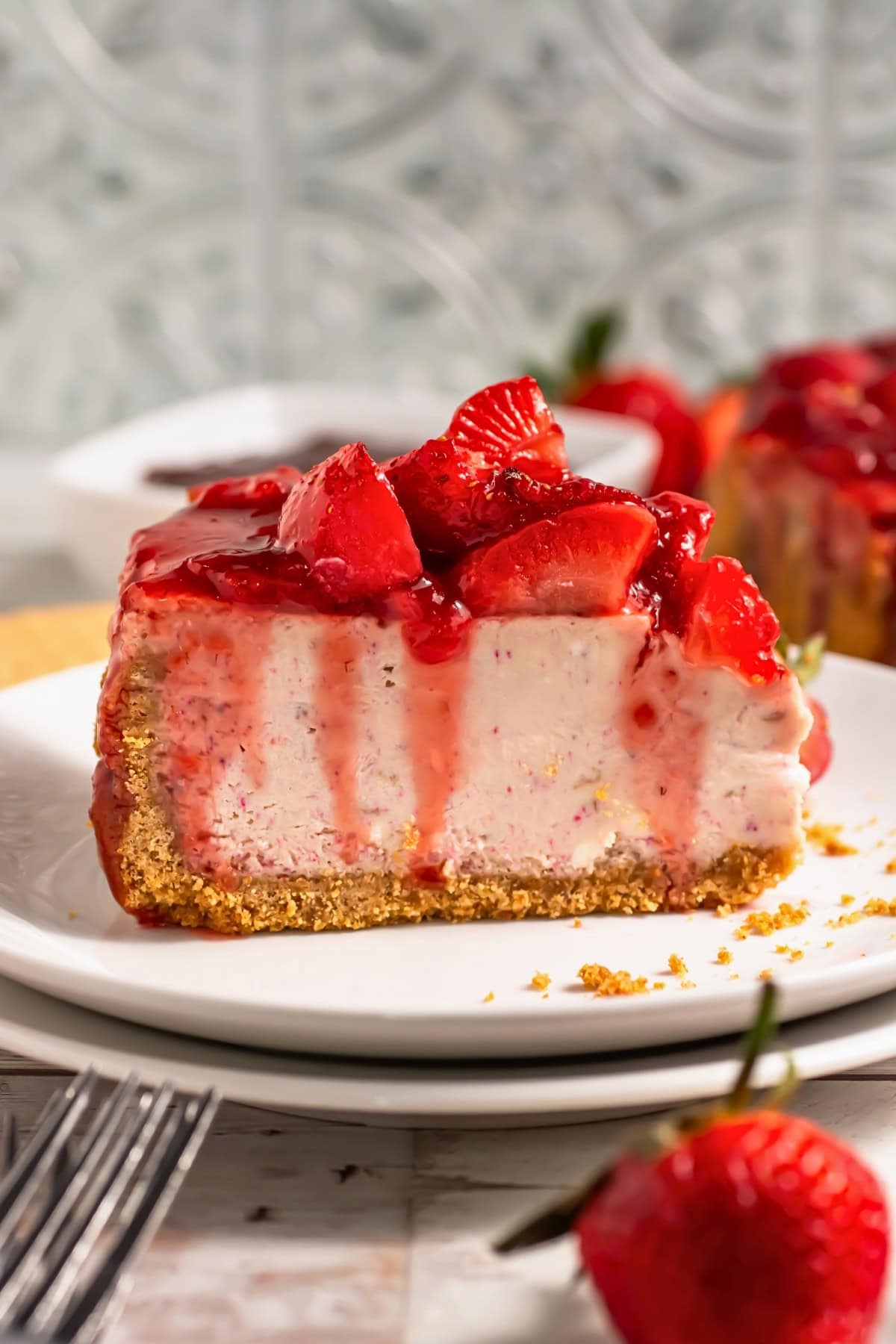 A slice of strawberry cheesecake with fresh strawberries and sauce on top.