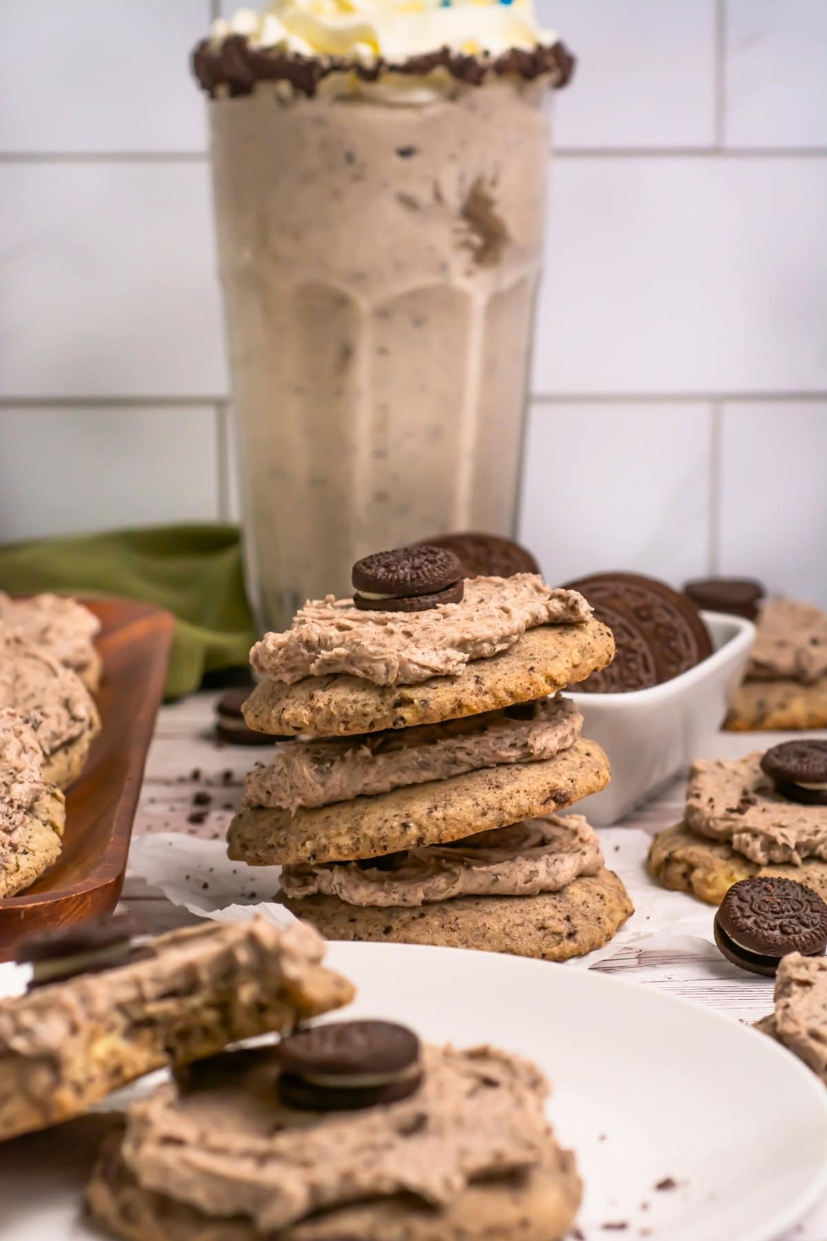 Stacked cookies with cream and mini cookies, with a milkshake in the background.