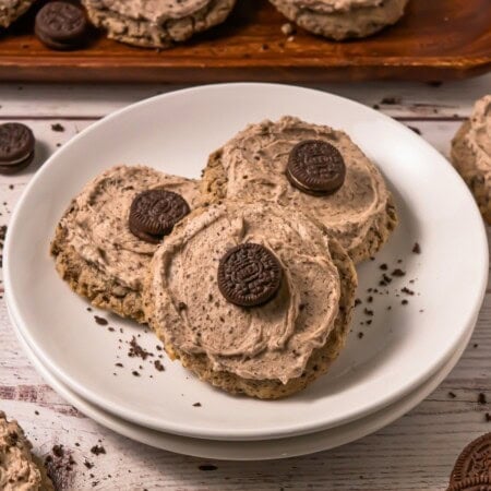 Three cookies with Oreo cream frosting and mini Oreo cookies on a white plate.