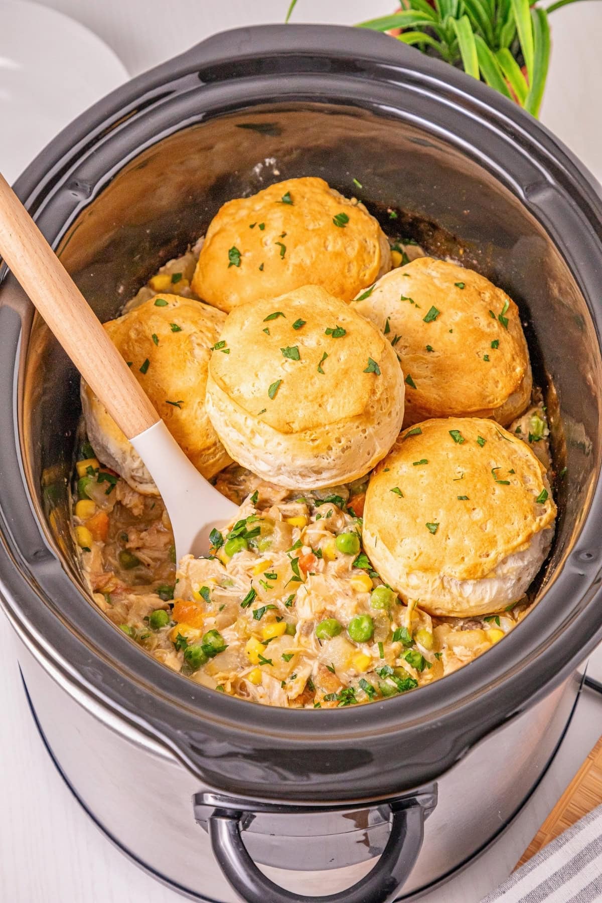 Slow cooker chicken pot pie topped with golden biscuits and sprinkled herbs.