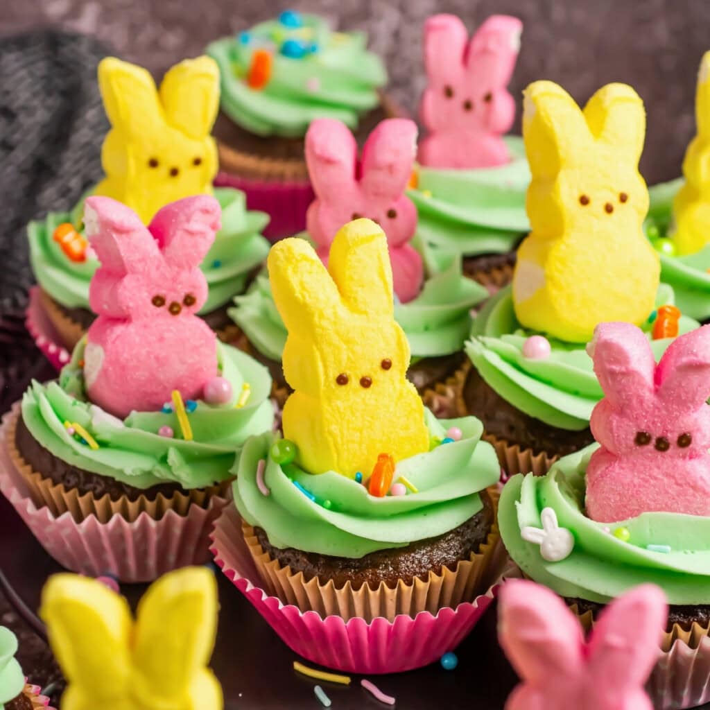 Chocolate cupcakes with green frosting, topped with pink and yellow bunny Peeps.