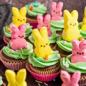 Chocolate cupcakes with green frosting, topped with pink and yellow bunny Peeps.