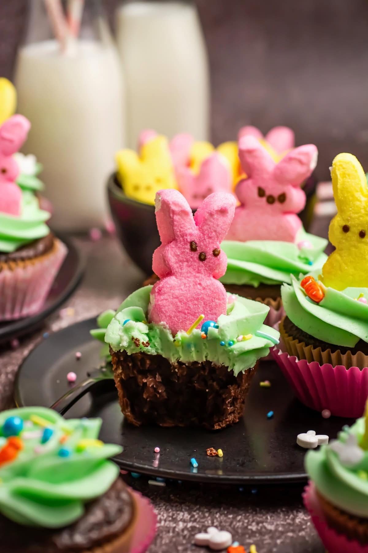 Cupcake topped with green icing and a pink bunny marshmallow, with sprinkles.