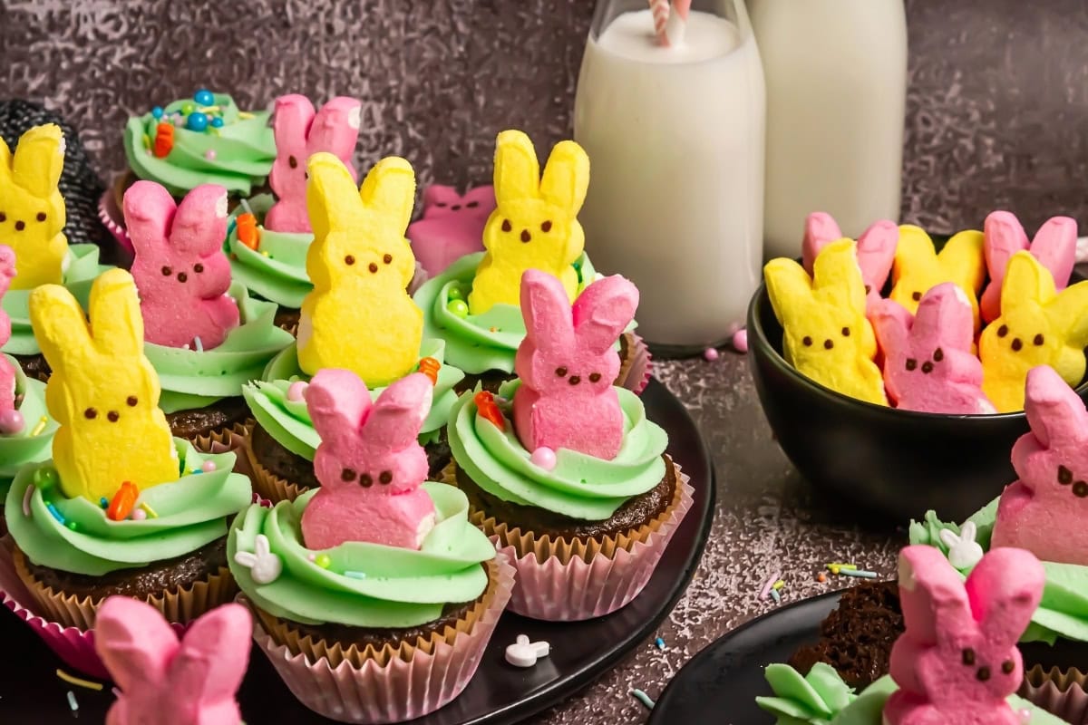 Chocolate cupcakes topped with green frosting and pink and yellow bunny marshmallows.
