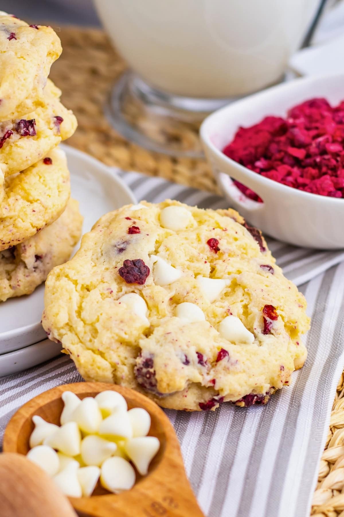 A white chocolate and berry cookie with white chips and dried berries nearby.