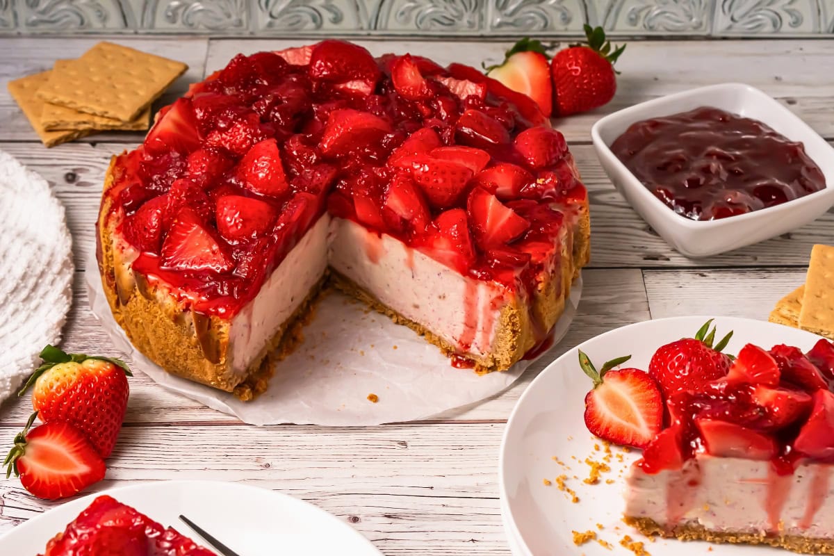 Strawberry cheesecake with fresh strawberries and sauce, served on plates.