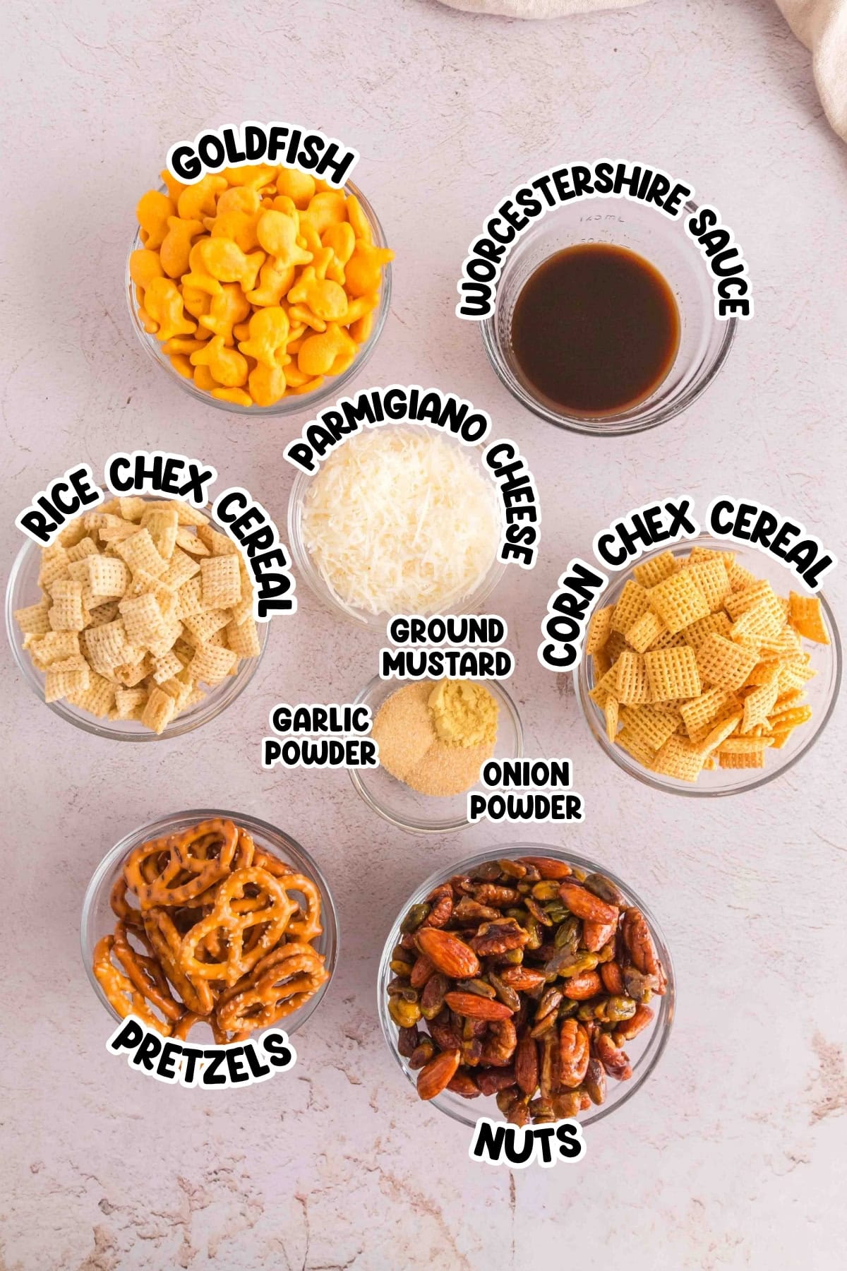 Seven bowls with snacks and seasonings labeled: goldfish, cereals, cheese, nuts, sauce.