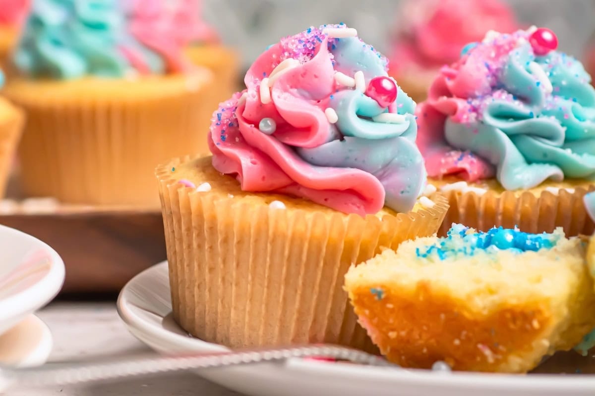 Cupcakes with pink and blue swirled frosting and colorful sprinkles on top.