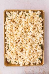 A baking sheet filled with freshly popped popcorn on a light-colored surface.
