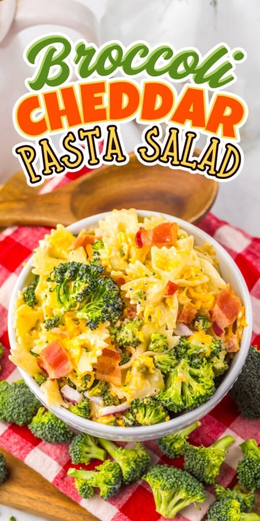 A bowl of broccoli cheddar pasta salad on a red checkered cloth with veggies.