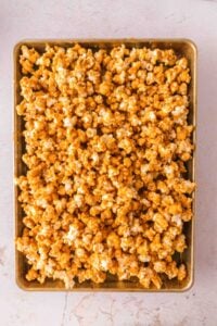 A baking tray filled with caramel popcorn on a light surface.