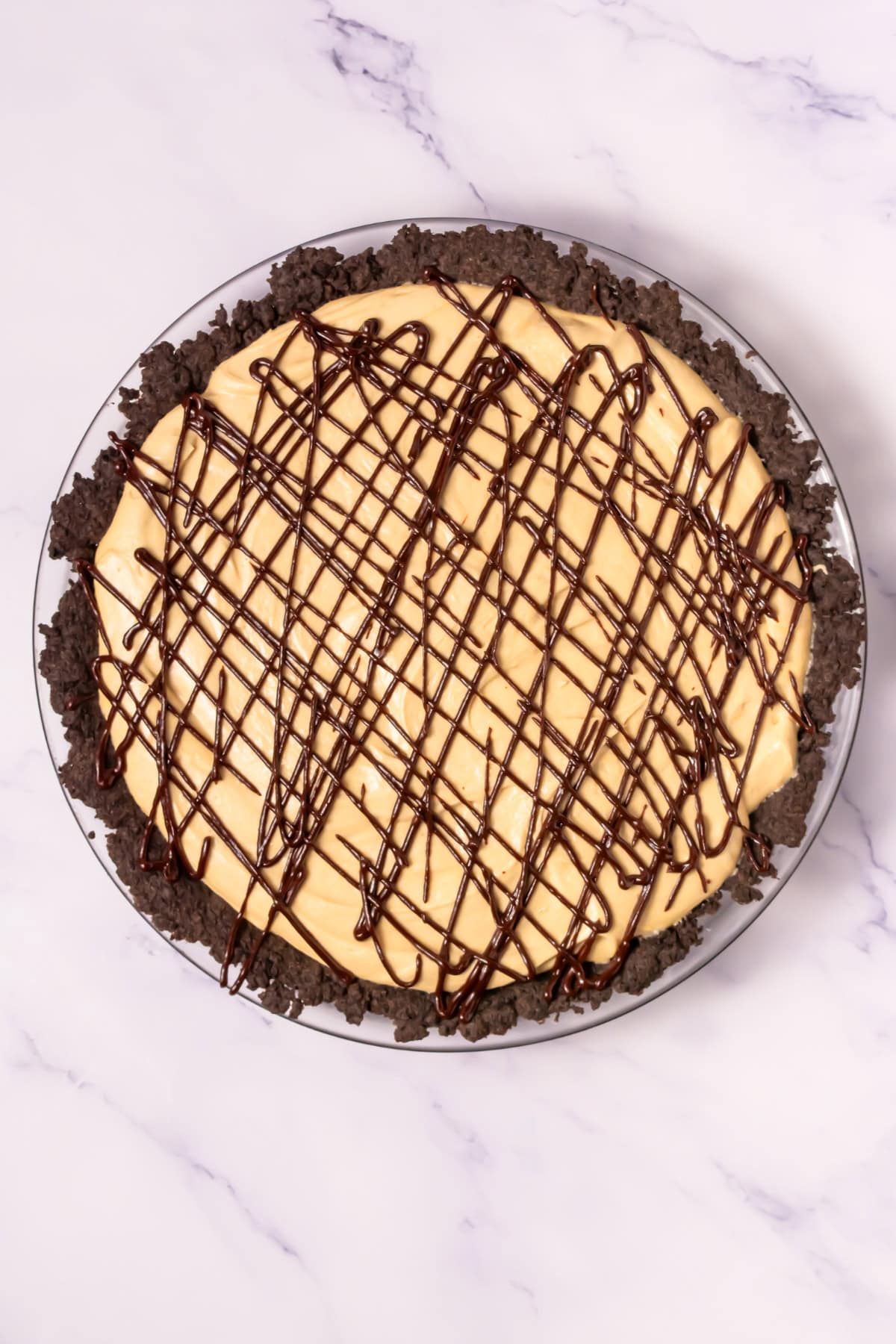 A peanut butter pie with chocolate drizzle and a chocolate cookie crust.