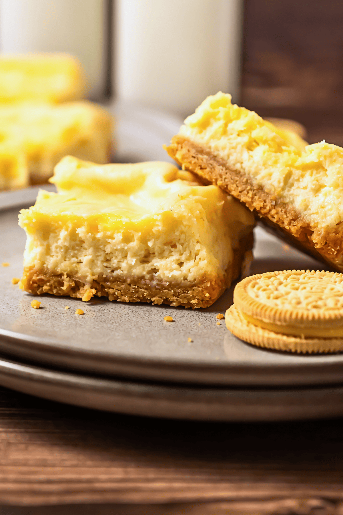 Lemon cheesecake bars with golden cookie crust on a gray plate.