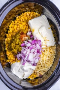 Corn, cream cheese, sour cream, onions, cheese, and spices in a slow cooker.