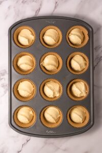 Muffin tin with paper liners filled with cupcake batter, ready to bake.