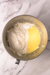A mixing bowl with flour and wet ingredients on a marble countertop.