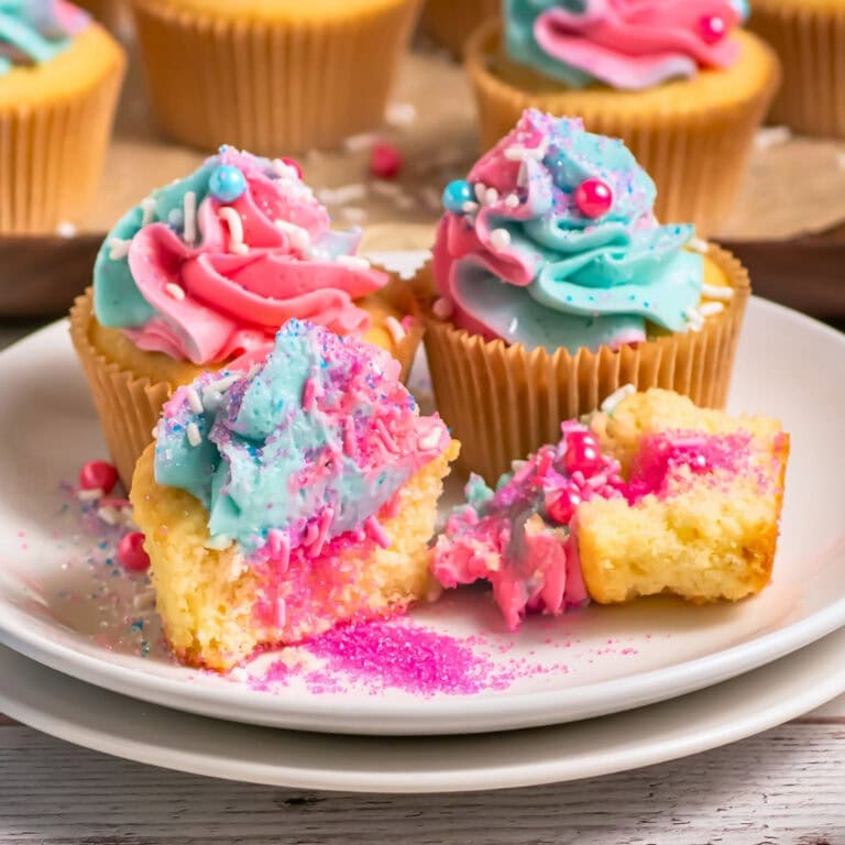 Vanilla cupcakes with pink and blue frosting, sprinkles, and colorful filling.