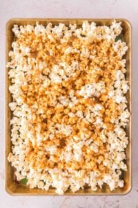 Popcorn covered in caramel spread out on a baking sheet.