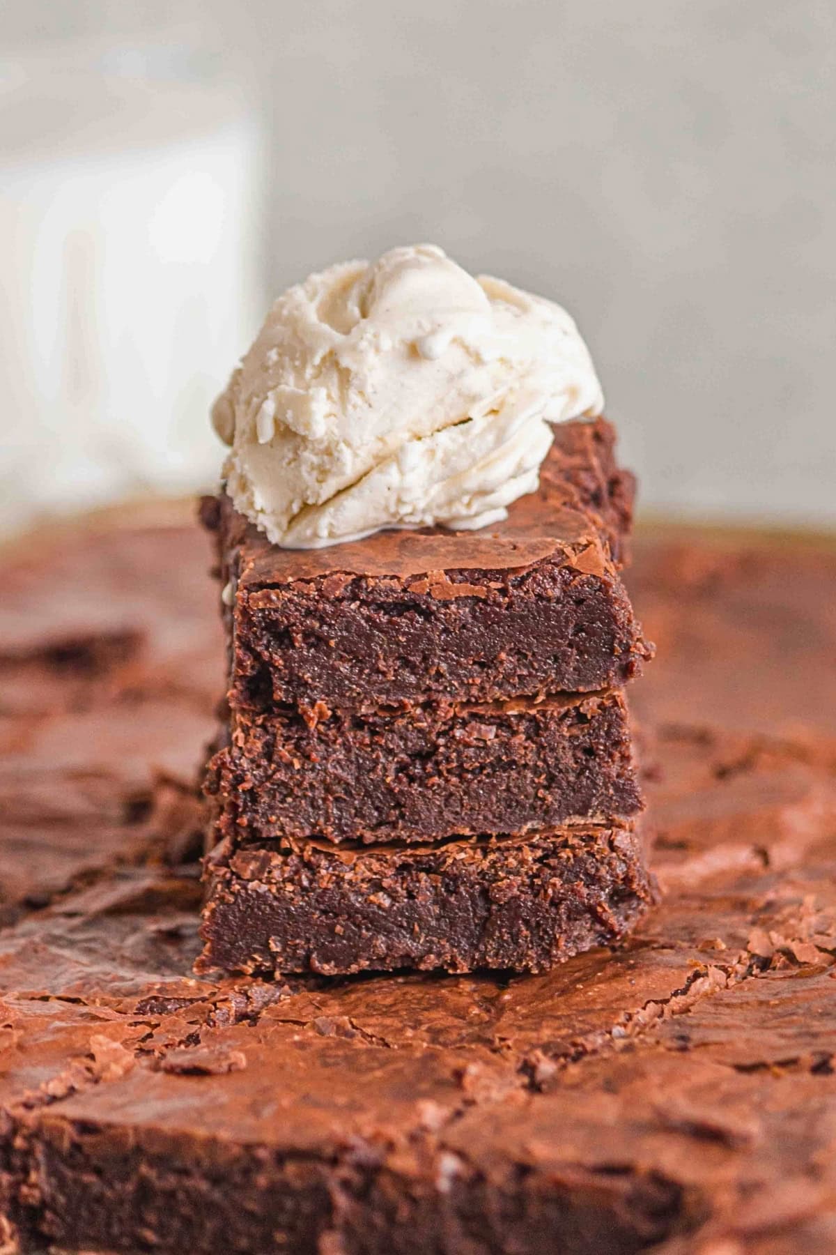 Three stacked brownies topped with a scoop of vanilla ice cream.