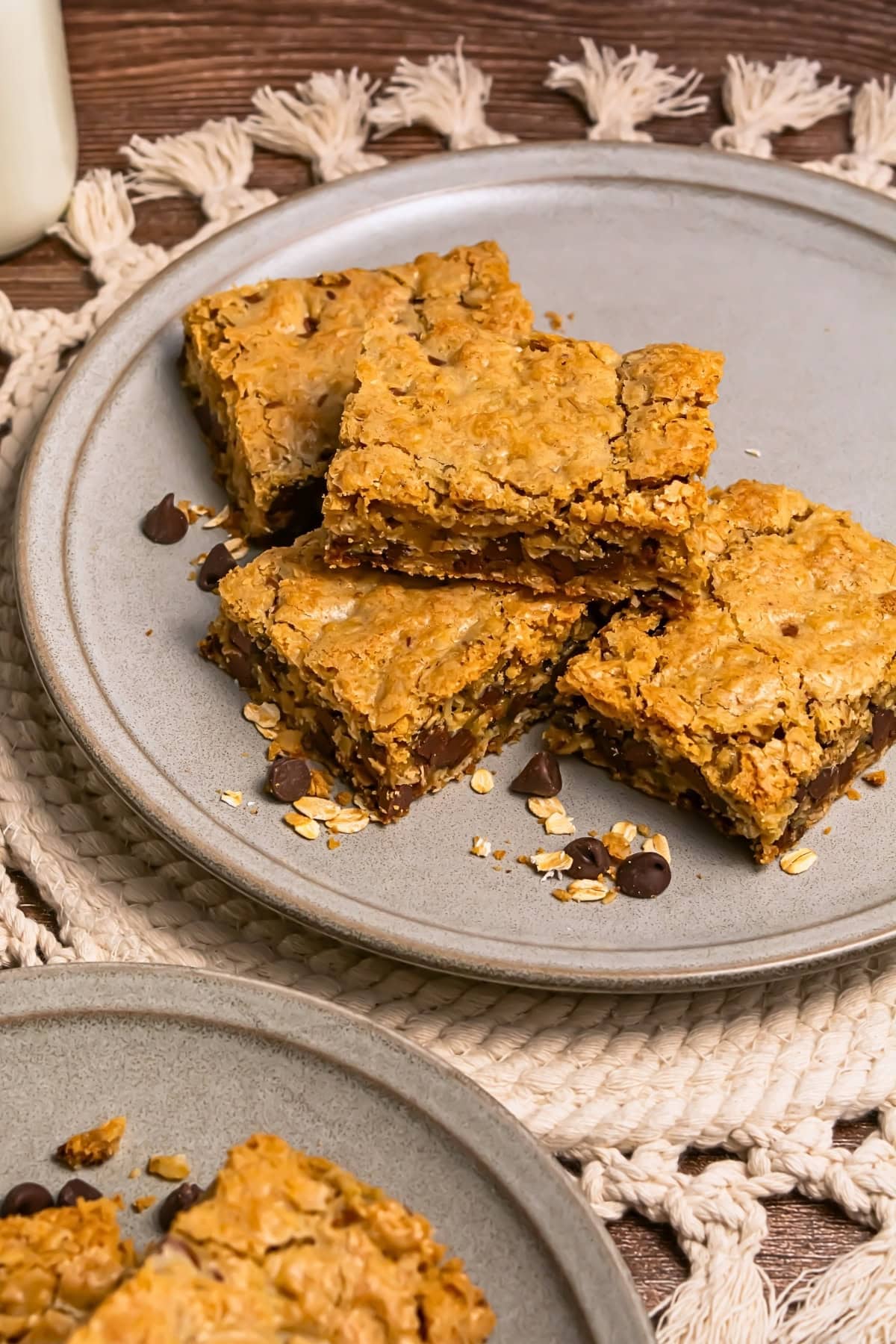 Four oat and chocolate chip bars stacked on a ceramic plate.