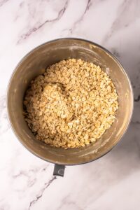 Mixing bowl with oatmeal cookie dough on a marble countertop.