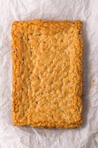A large rectangular oatmeal cookie bar on crinkled parchment paper.