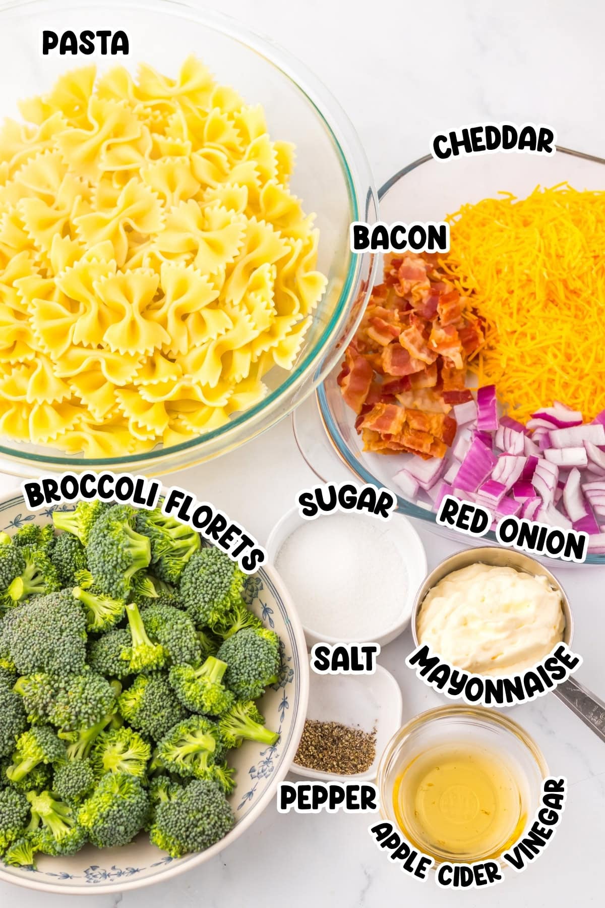 Bowls of pasta, broccoli, cheddar, bacon, red onion, and various seasonings.