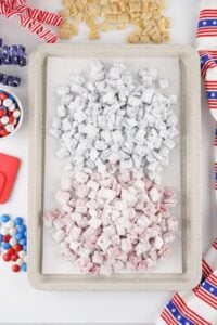 Tray of red, white, and blue powdered snack mix with festive decorations around.