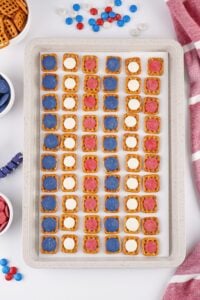 A baking tray with pretzel snacks topped with red, white, and blue candies.