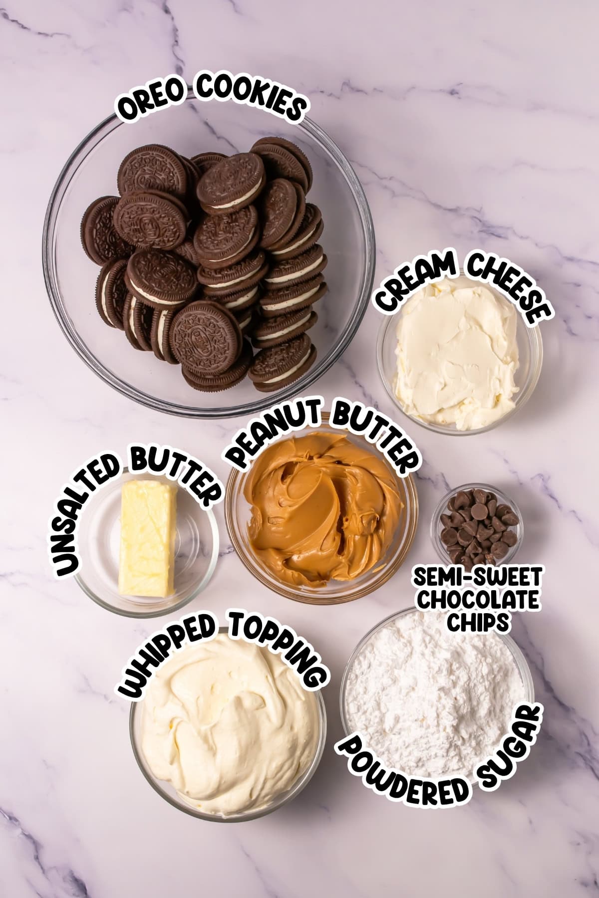 Bowls of Oreo cookies, cream cheese, peanut butter, butter, whipped topping, chocolate chips, and powdered sugar.