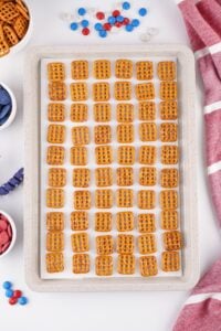 A baking tray with neatly arranged square pretzels on parchment paper.